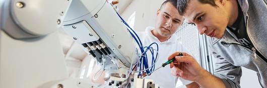 Two techs fine tuning a robotic arm