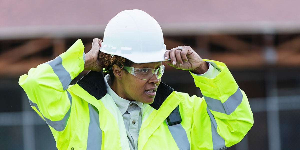 Person wearing PPE while putting on a hard hat