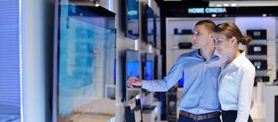 Young couple shopping for a tv in an electronic store.