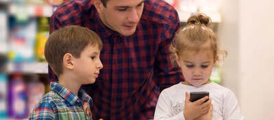 Family at a store looking at a smartphone while shopping