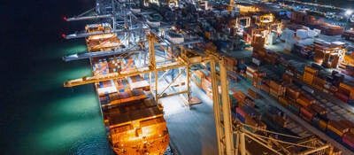 A cargo ship docked with many shipping containers