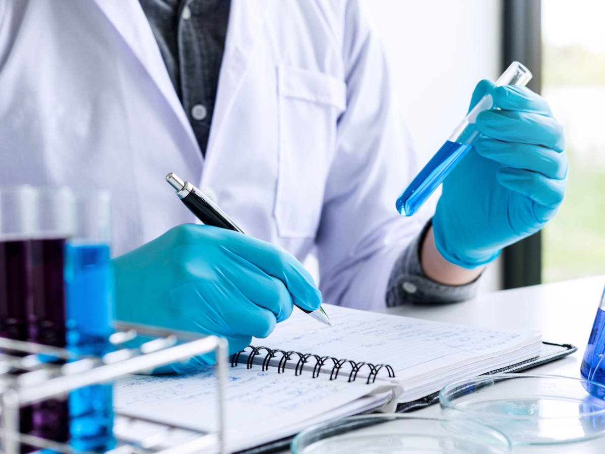 a laboratory technician writing chemical information in a log