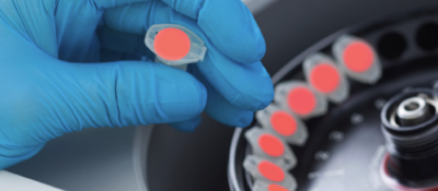 Closeup of hand in blue rubber glove holding a vial